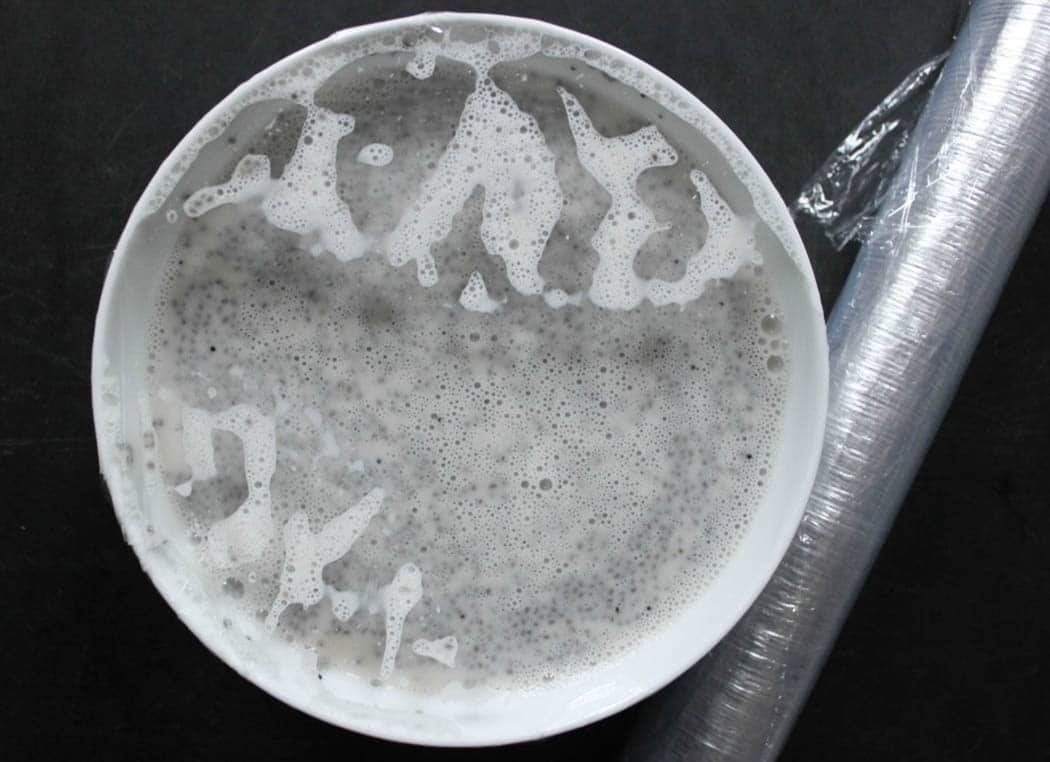 Ingredients for chia pudding mixed in a bowl and covered with plastic before refrigeration.