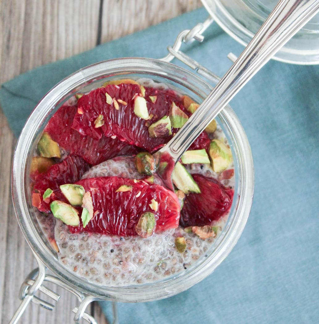 Close-up of a spoonful of chia seed pudding with blood orange and pistachios.