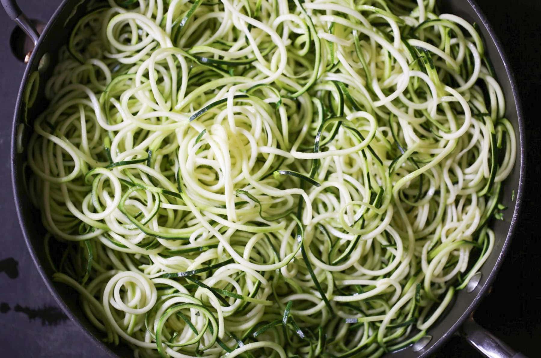 Uncooked zucchini noodles in the pan.