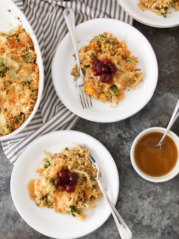 Overhead view of two portions of Thanksgiving Quinoa Bake topped with cranberry sauce with the casserole dish peeking in from the left side.